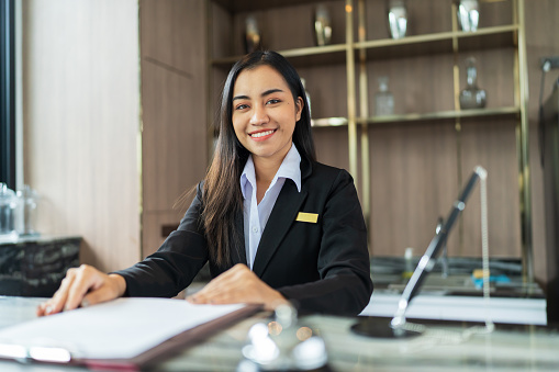 Beautiful asian hotel receptionist in  uniforms at desk in lobby FriendlyÂ and welcome staff in hotel reception counter