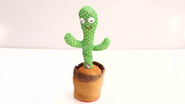 Dancing cactus children's toy on a white table with white wall background