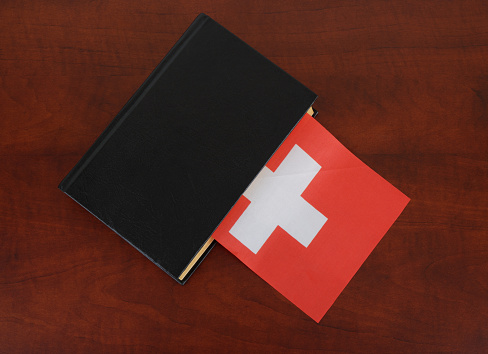 Black legal book with  flag of Switzerland. Laws in Switzerland.