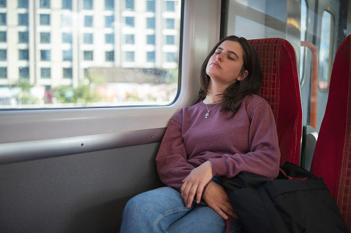 Young female student sleeping in the public transportation.