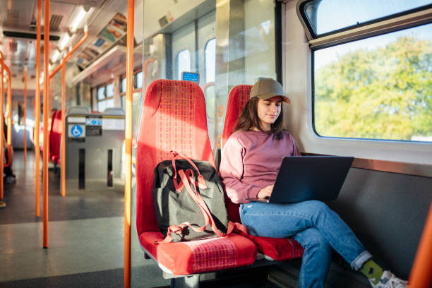 istock Female college student using laptop in the train on the way to class. 1766484867