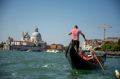 View from a Gondola in Venice showing another gondola and gondolier infant as well as having Venice in the background.