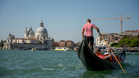 View from a Gondola in Venice showing another gondola and gondolier infant as well as having Venice in the background.