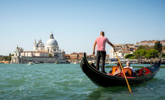 View from a Gondola in Venice showing another gondola and gondolier infant as well as having Venice in the background.