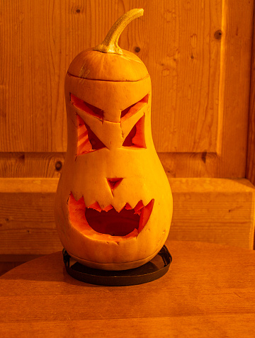 Pumpkin lantern, Halloween attribute. A lantern, carved from a pumpkin, a head with a frightening or funny face. Jack-o-lantern. Will-o-the-wisp. Scary face with a grin on a black background.