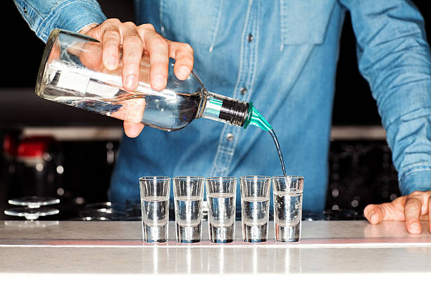 Bartender Pouring Vodka Into Shot Glasses At Bar Counter Midsection of male bartender pouring vodka into shot glasses at bar counter. Horizontal shot. vodka photos stock pictures, royalty-free photos & images