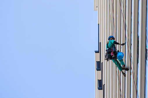 26 October 2023, Tokyo Japan. A man hanging from ropes from the side of a high-rise building in Tokyo, cleaning windows.