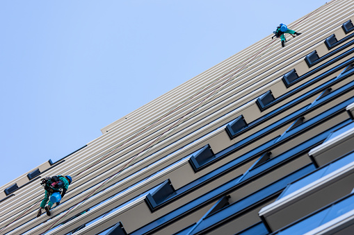 26 October 2023, Tokyo Japan. Men hang from ropes from the side of a high-rise building in Tokyo, cleaning windows.