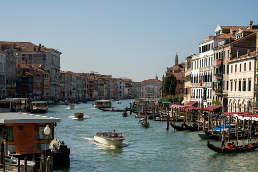 Famous canal within Venice showcasing multiple boats, including gondolas as well as some of the beautiful buildings Venice has to offer.