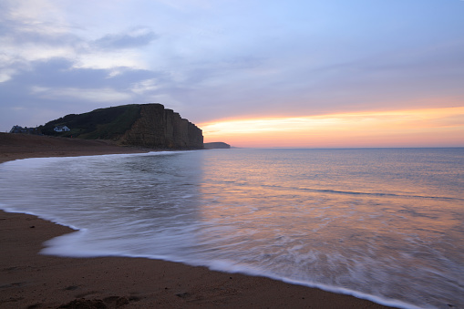 Beautiful sunset on the beach. Scenic seascape with rock during the low tide.