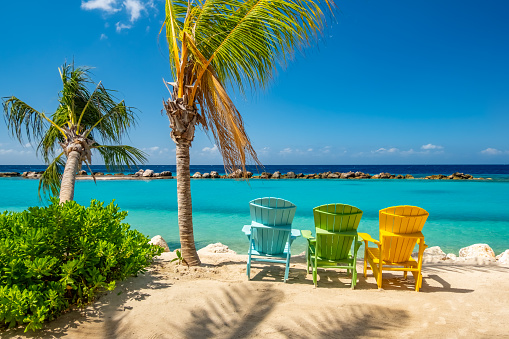 Beautiful coloured wooden chairs on a Caribbean beach