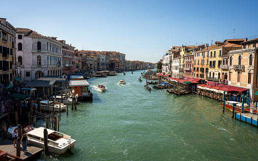 Famous canal within Venice showcasing multiple boats, including gondolas as well as some of the beautiful buildings Venice has to offer.