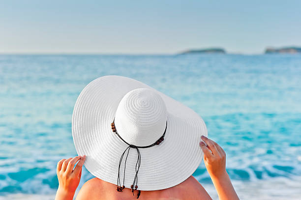 istock woman sunbathing on the beach and holding hands hat 176655000