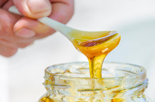istock hand is pouring honey from porcelan spoon drizzler 176655002