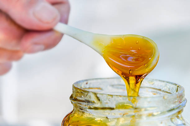 istock hand is pouring honey from porcelan spoon drizzler 176656810