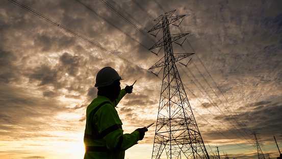 Silhouette of engineer man checking high-voltage power lines.