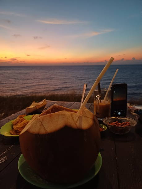 istock Coconut cocktail and snacks on a wooden table at sunset. 1766577179