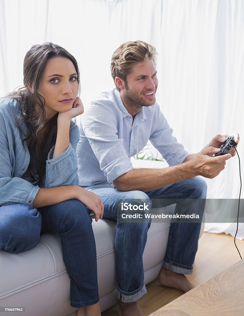 Triste donna infastidita perché la sua partner è la riproduzione di video giochi - Foto stock royalty-free di Noia