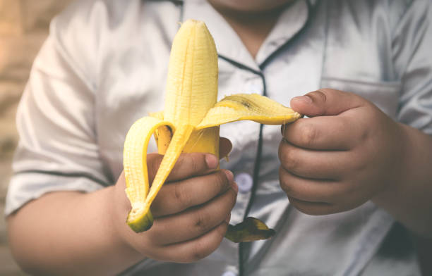 plátanos maduros en la mano de un niño - fashion palette fotografías e imágenes de stock