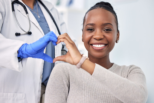Black woman, patient and doctor with smile, consultation and heart emoji for cardio health, checkup and appointment. Happiness, support and wellness for medicine, healthcare and physical examination