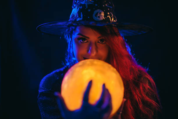 young woman dressed like a witch holding a crystal ball - fortune telling paranormal neon light prophet imagens e fotografias de stock