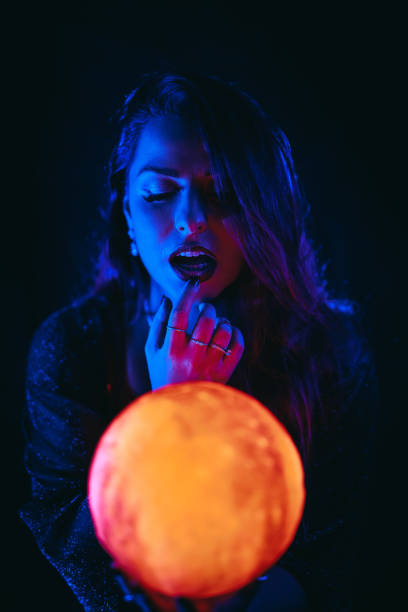 young woman holding a crystal ball under neon lights - fortune telling paranormal neon light prophet imagens e fotografias de stock