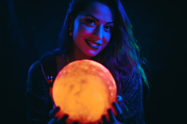 young woman holding a crystal ball under neon lights - fortune telling paranormal neon light prophet imagens e fotografias de stock