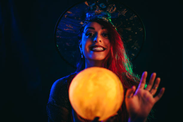 young woman dressed like a witch holding a crystal ball - fortune telling paranormal neon light prophet imagens e fotografias de stock