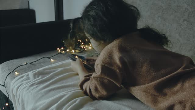 Little girl looking at old pictures on a Christmas night. Christmas lights around. Christmas and leisure concept.