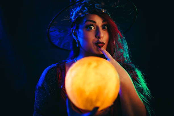 young woman dressed like a witch holding a crystal ball - fortune telling paranormal neon light prophet imagens e fotografias de stock