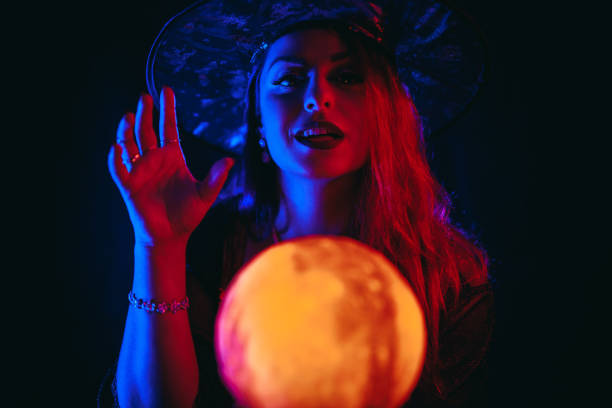 young woman dressed like a witch holding a crystal ball - fortune telling paranormal neon light prophet imagens e fotografias de stock