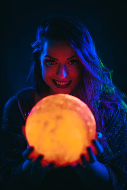 young woman holding a crystal ball under neon lights - fortune telling paranormal neon light prophet imagens e fotografias de stock