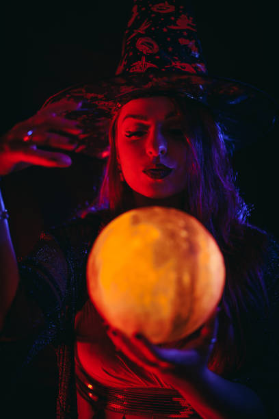 young woman dressed like a witch holding a crystal ball - fortune telling paranormal neon light prophet imagens e fotografias de stock