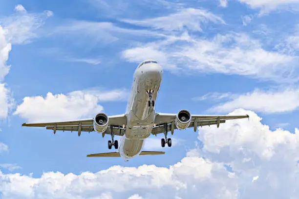 Airbus A321 passenger plane landing at the airport, under a blue sky with white clouds