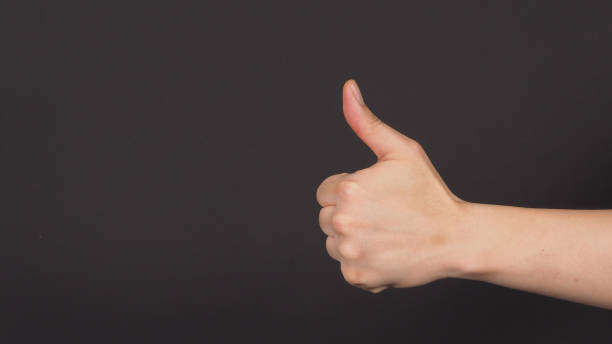 male model's backhand doing The thumbs up or like hand sign on black background.