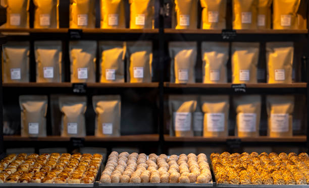 Three trays of assorted pine nut panellets and coconut sweets and toasted cream fresh from the gourmet artisan oven with jars and sacks of ingredients and flour in the background. Typical artisan.