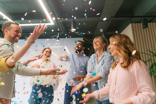 Photo of a group of coworkers having a happy occasion and celebrating together in their workplace