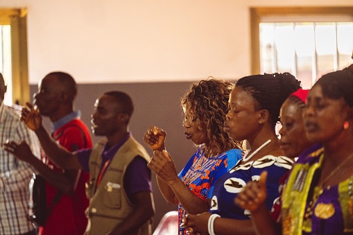 Abidjan, Ivory Coast – February 26, 2023: A group of people in a church in Abidjan, Cote d'Ivoire, praying together