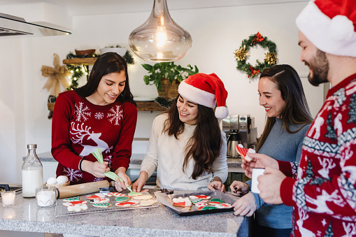 Latin friends baking and tasting Christmas cookies at home together in Mexico Latin America