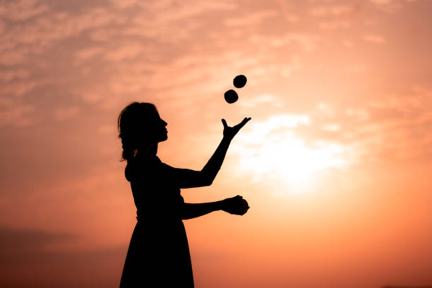 Young lady juggling, side view (blurred motion) in nature at sunset.