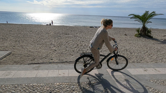 She is riding along a cobblestone promenade by the Mediterranean Sea, Liguria