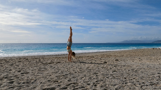 She is practising handstands  by the Mediterranean Sea, Liguria