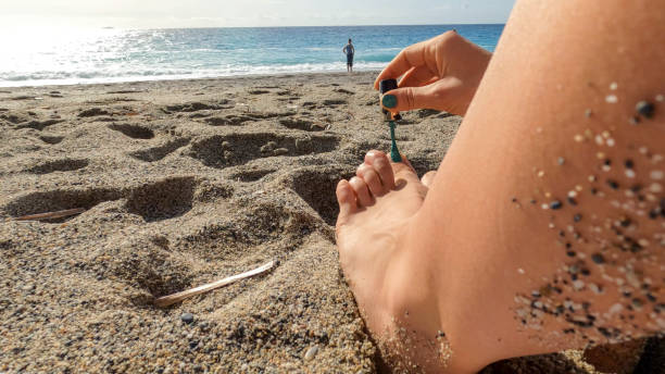 Detail of young woman painting her toes, Mediterranean Sea, Liguria