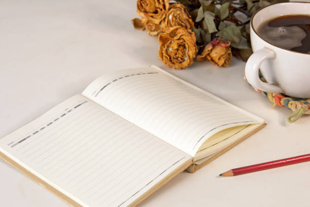istock Open a blank white notebook, pencil, flowers and coffee cup on the desk 1766719594