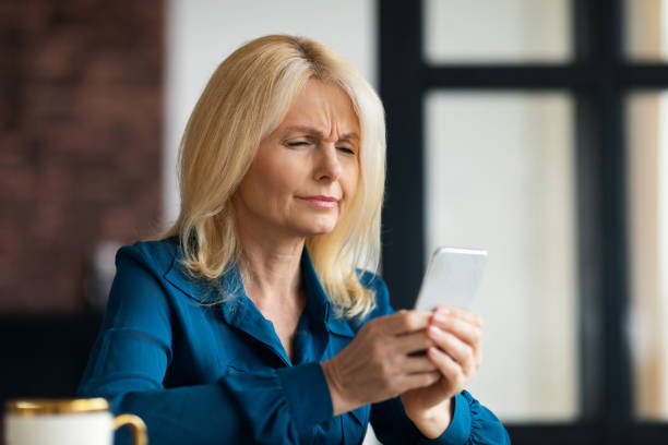 istock Myopia concept. Mature woman squinting while looking at mobile phone screen at home, free space 1766721405