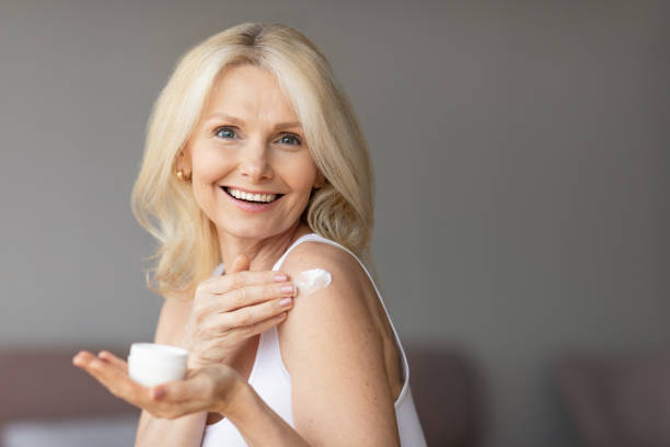 istock Good-looking mature lady using body lotion or applying moisturizing or nourishing cream on her shoulder after shower 1766722059