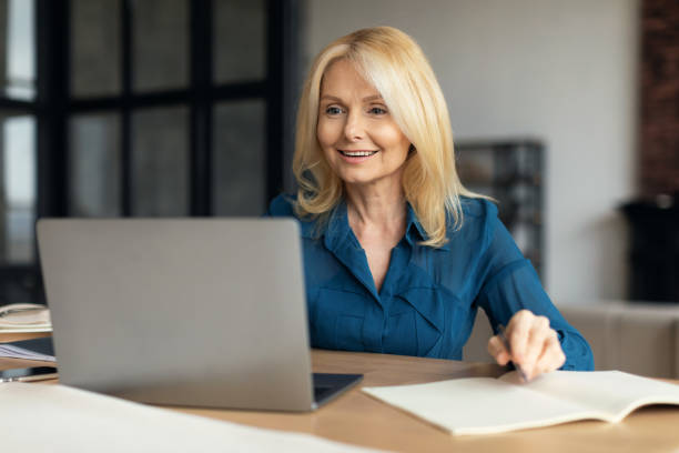 istock Remote work. Smiling mature woman entrepreneur using laptop at home, looking at computer screen smiling and taking notes 1766722075