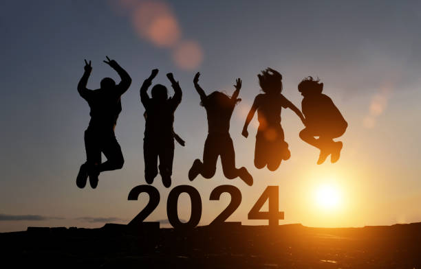 un gruppo felice di persone celebra il salto per il nuovo anno 2024. concetto per vincere la vittoria. silhouette di amici salta all'ora del tramonto sulle montagne. - celebration group of people family crowd foto e immagini stock