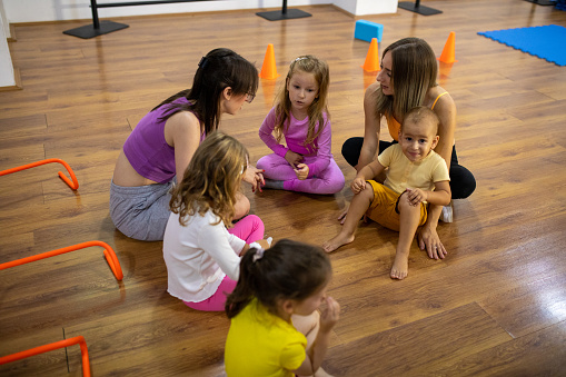 Group of children sitting on the floor with their dance teachers at the dance studio.