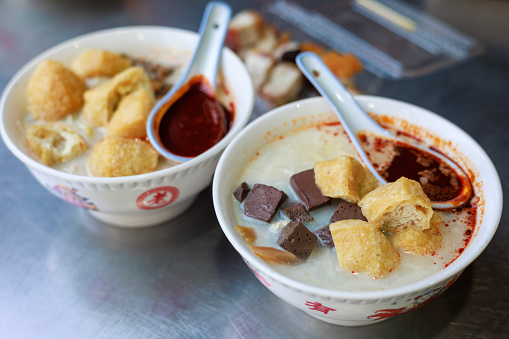 Penang's famous Curry Mee is a flavorful dish served with coagulated pig's blood, prawn, cuttlefish, cockles and topped with spicy chili paste.